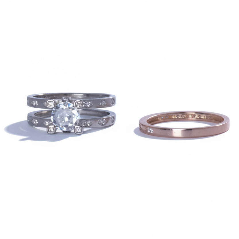 Two diamond rings on a reflective surface with a light gray background