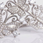Silver butterfly-shaped jewelry with clear gemstones on a light background