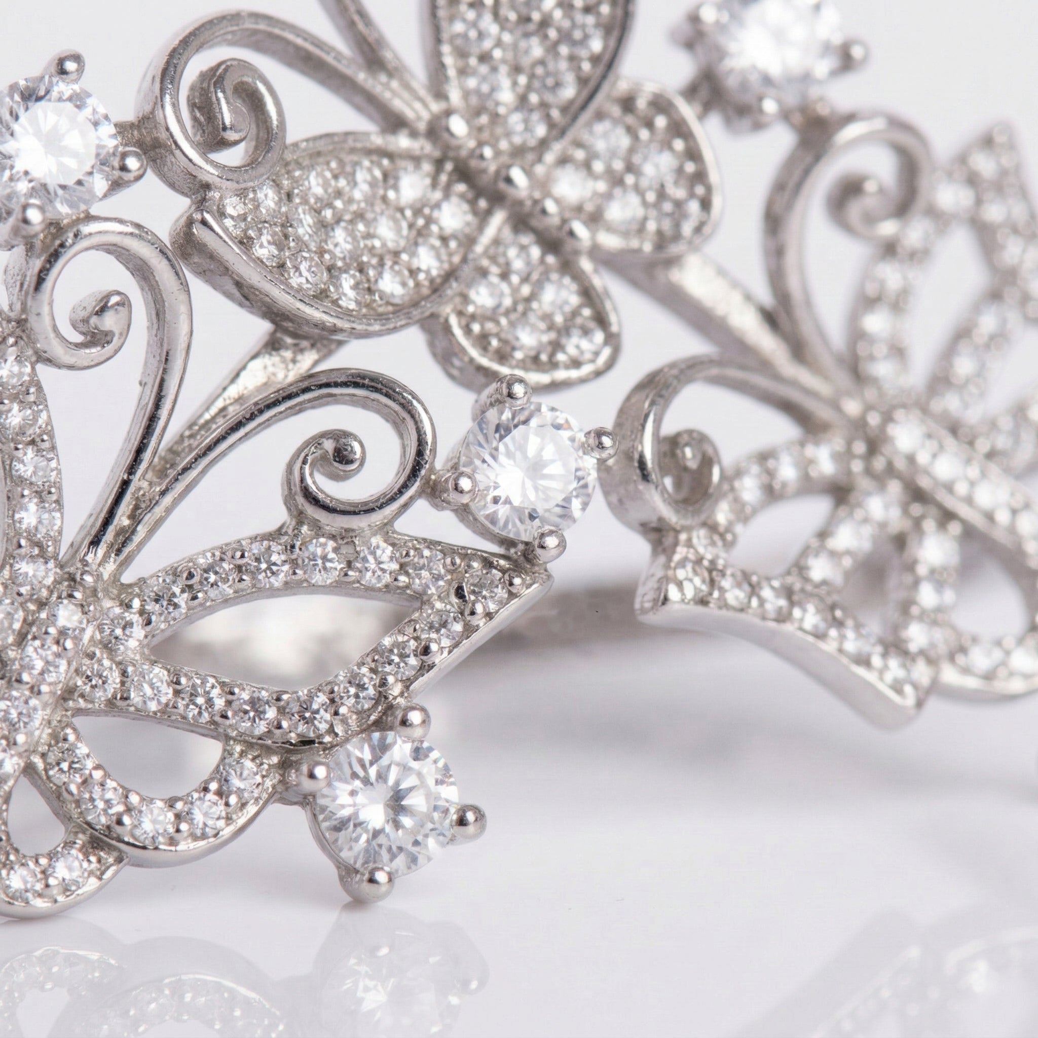 Silver butterfly-shaped jewelry with clear gemstones on a light background