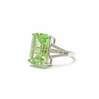 Green gemstone ring held by a hand against a dark background
