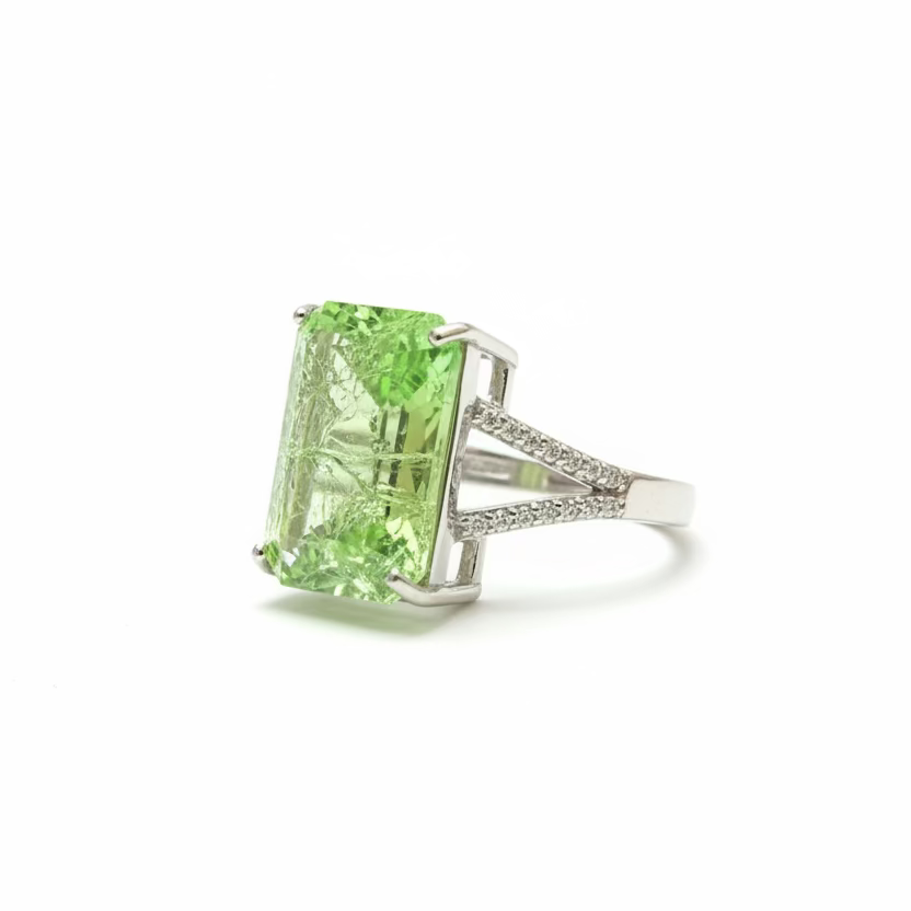 Green gemstone ring held by a hand against a dark background