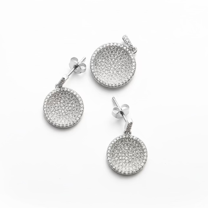 Pair of silver earrings and pendant  with circular designs on a white background