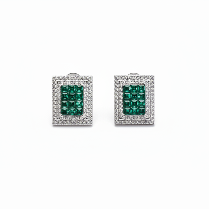 Pair of emerald green gemstone earrings with silver frames on a white background