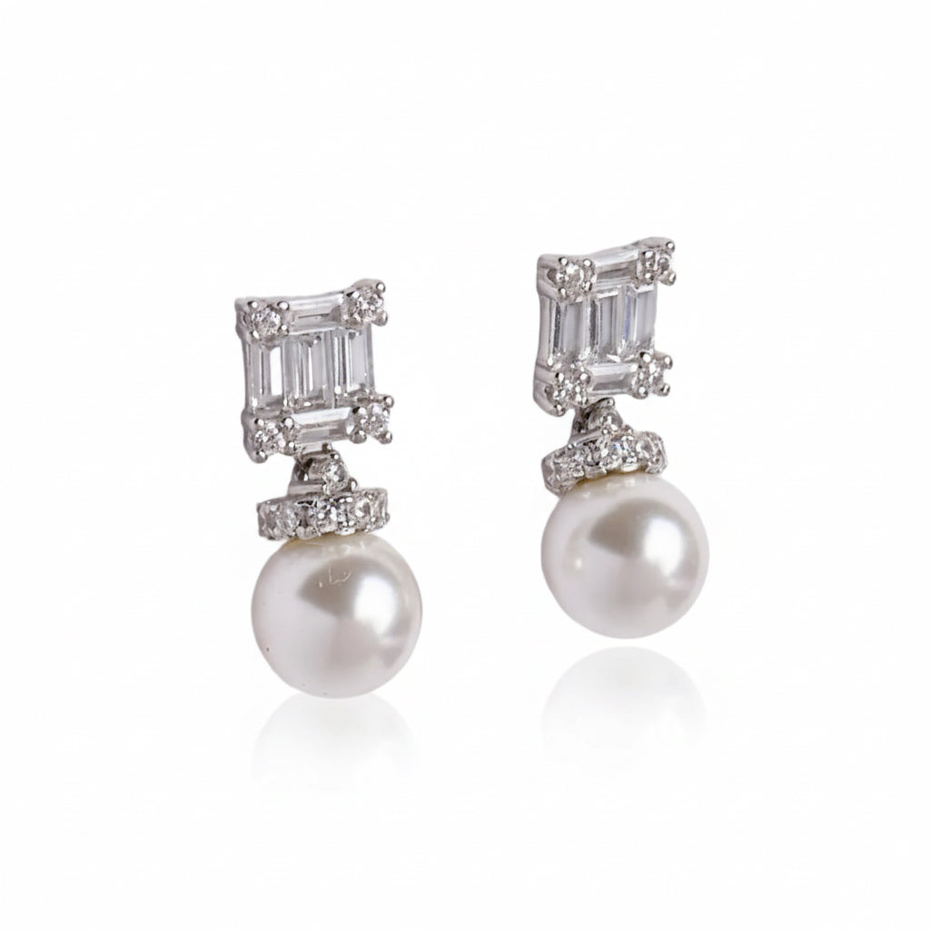Pair of pearl and diamond earrings on a light gray background