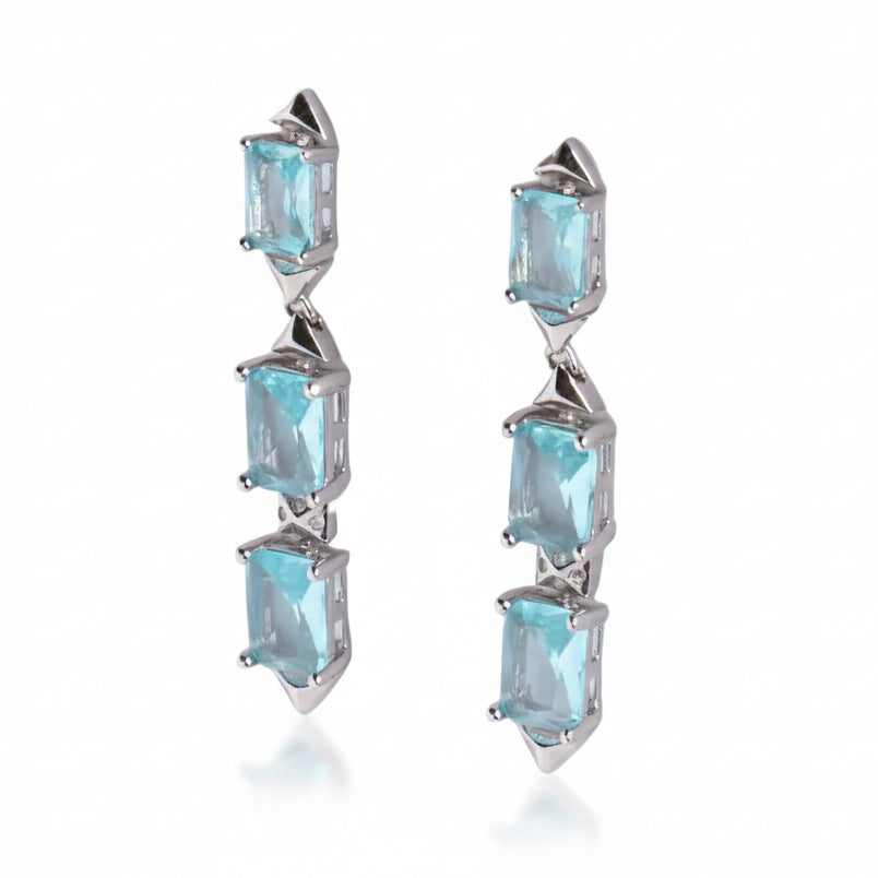 Pair of earrings with blue gemstones on a light gray background