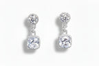 Pair of silver earrings with clear gemstones on a white background