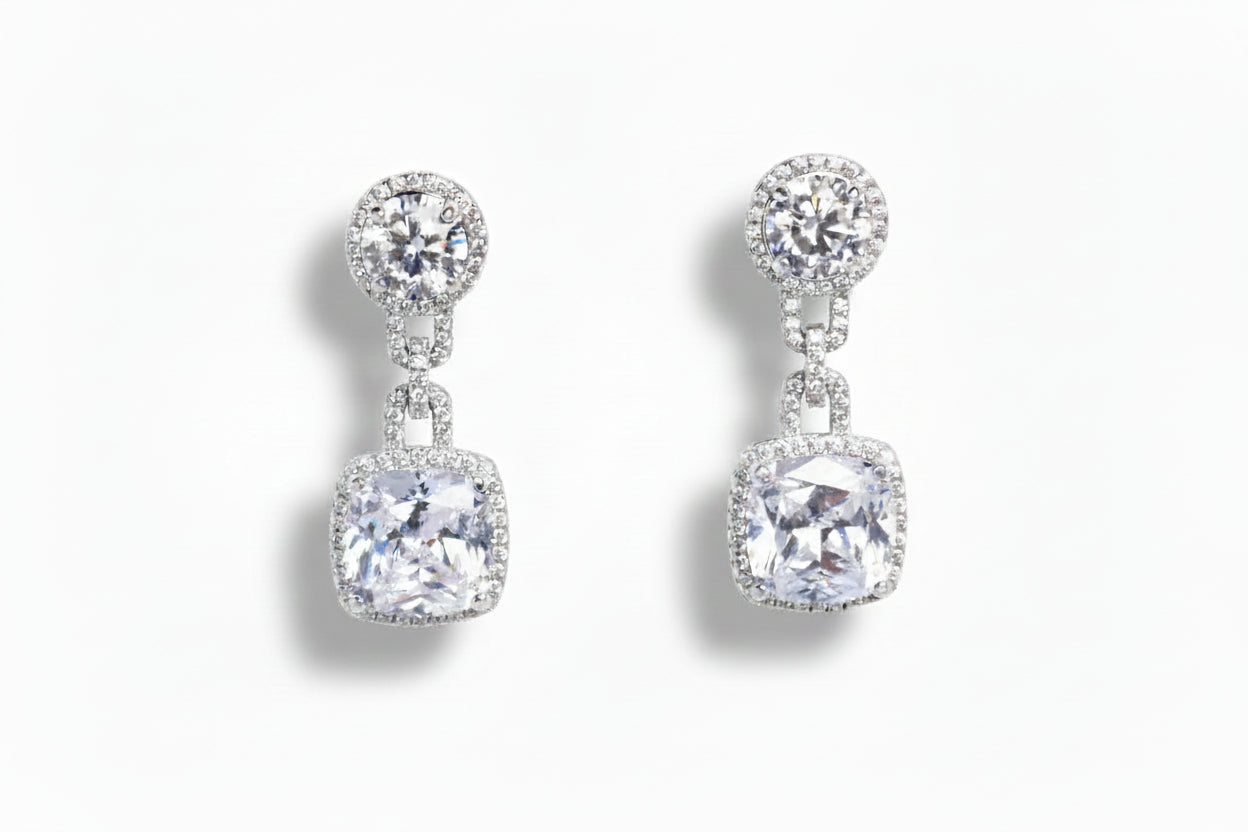 Pair of silver earrings with clear gemstones on a white background