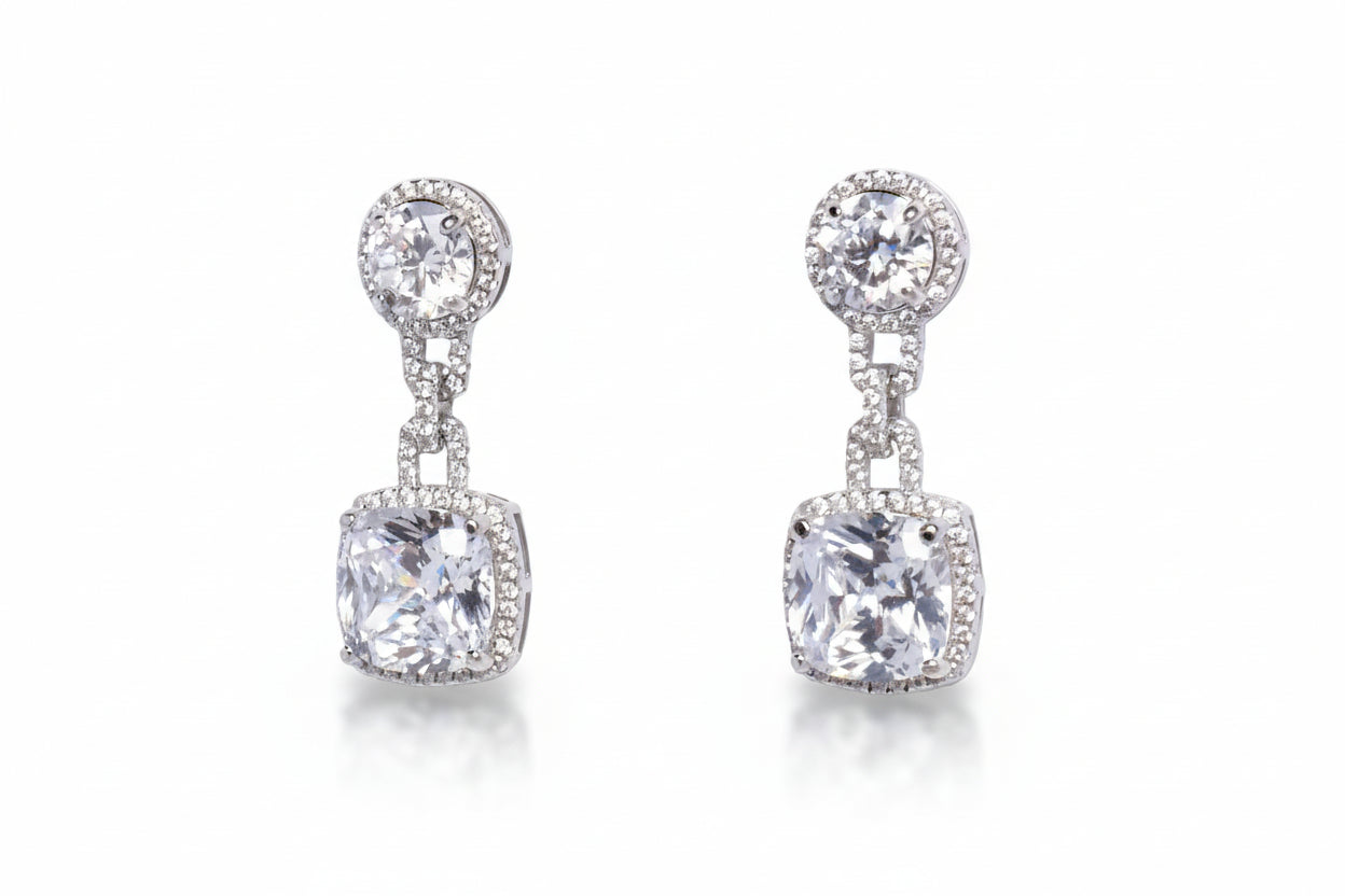 Pair of silver earrings with clear gemstones on a light gray background