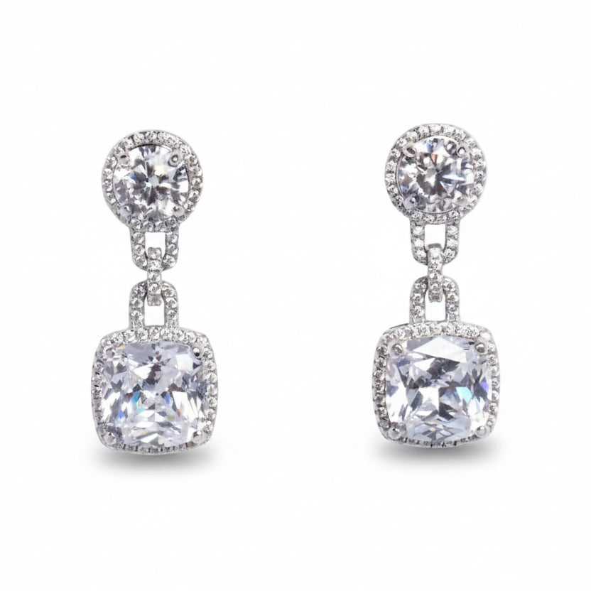 Pair of silver earrings with clear gemstones on a light gray background