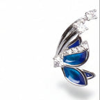 Butterfly-shaped earrings with blue accents and clear stones on a white background