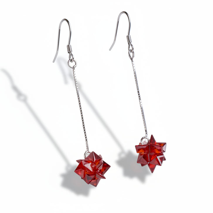 Red star-shaped earrings on silver hooks against a white background