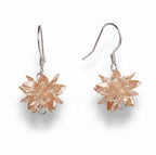 Pair of floral earrings with a metallic finish on a white background