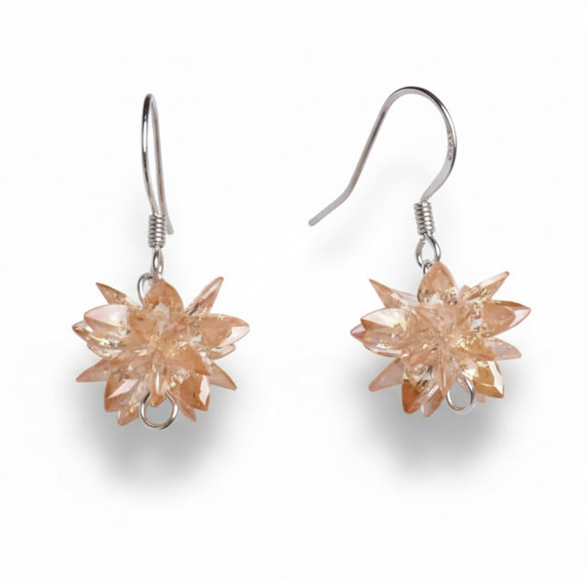 Pair of floral earrings with a metallic finish on a white background