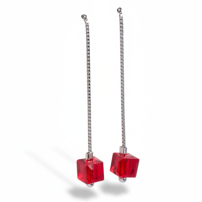 Pair of earrings with red cube-shaped beads on silver chains against a white background