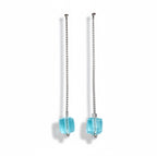 Pair of earrings with blue cube-shaped drops on a light gray background