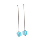 Pair of earrings with blue cube-shaped drops on a white background
