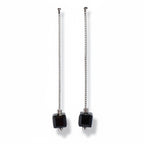 Pair of earrings with black square beads and chain extensions on a light gray background