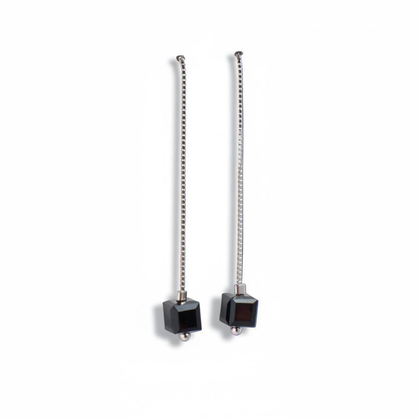 Pair of earrings with black cube-shaped drops on a white background