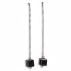 Pair of earrings with square black beads on a white background