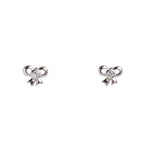 Pair of silver bow-shaped earrings with a central gemstone on a light gray background