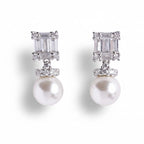 Pair of pearl earrings with diamond-like stones on a white background