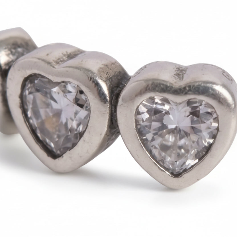 Silver heart-shaped earrings with clear gemstones on a white background