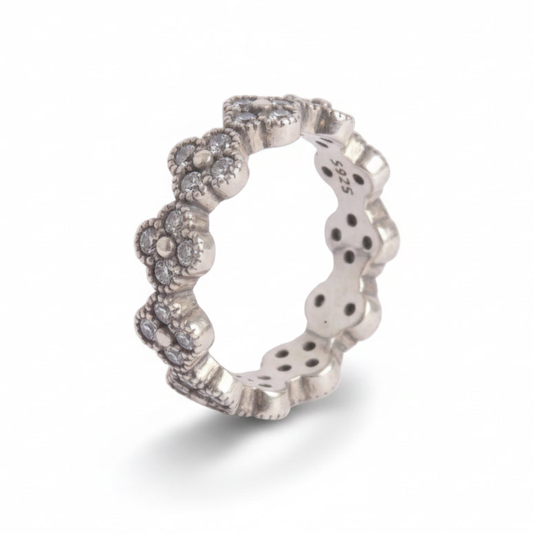 Silver ring with floral designs on a light gray background